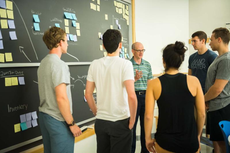 Student standing with professor by a chalkboard a class