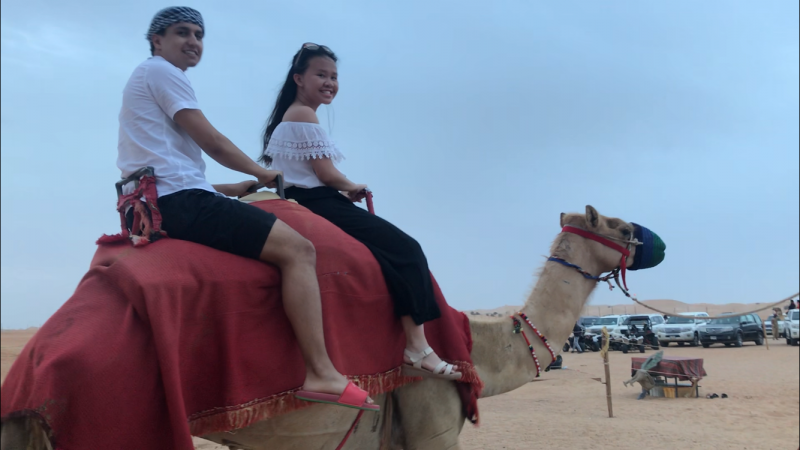 Two students riding a camel