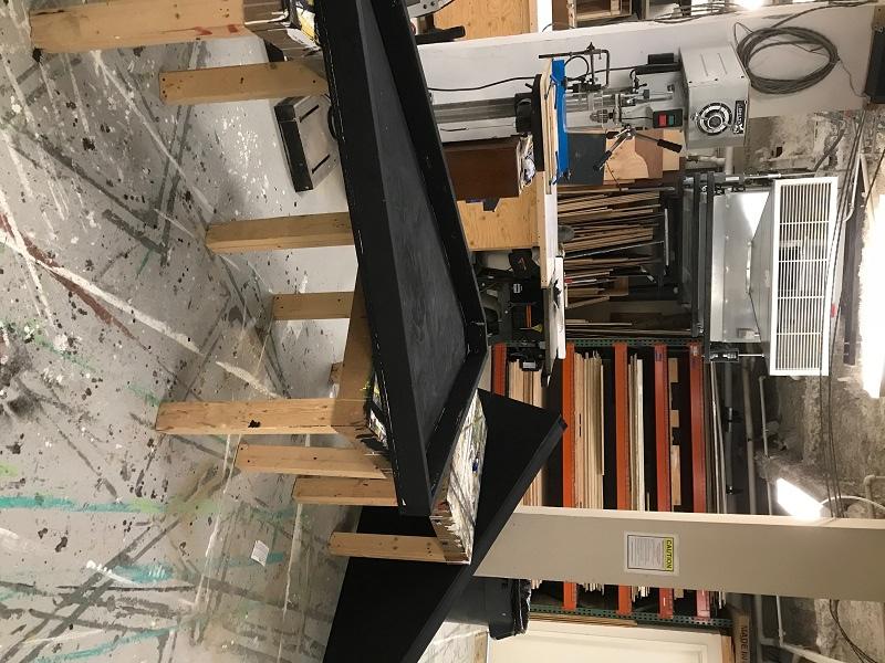 Two wooden panels painted black and leaning against tables in the scene shop