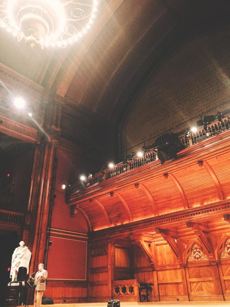 a man standing on stage in Sanders Theatre