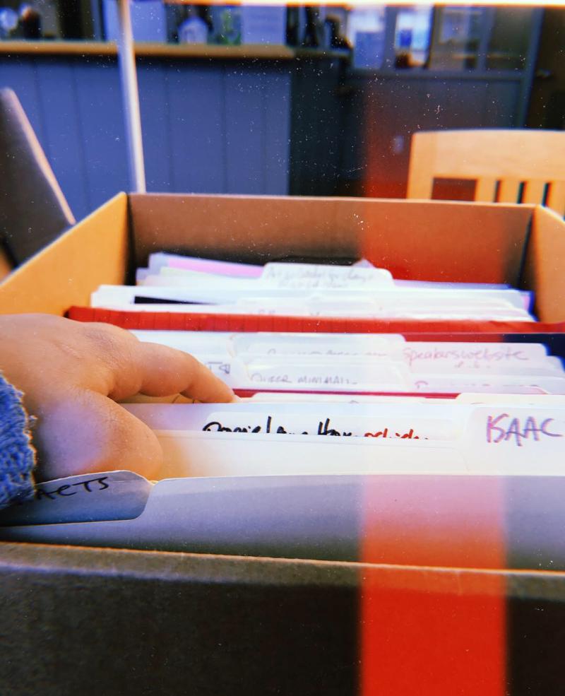 Hand going through files in a box at an archive 