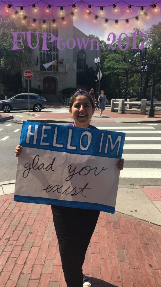 student holding sign that reads: 'Hello I'm glad you exist"