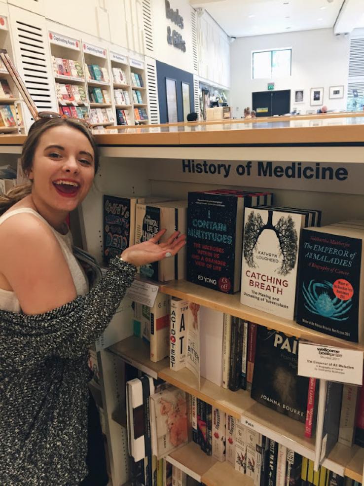 a student in front of bookshelf labeled History of Medicine