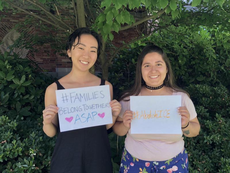 Two students holding signs that read: 'families belong together asap' and 'abolish ICE'