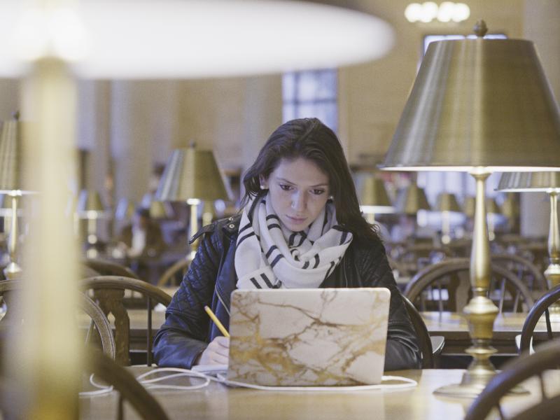 Female student working at a laptop in Widener library 