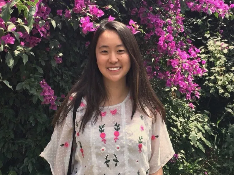 Student standing in front of flowers.