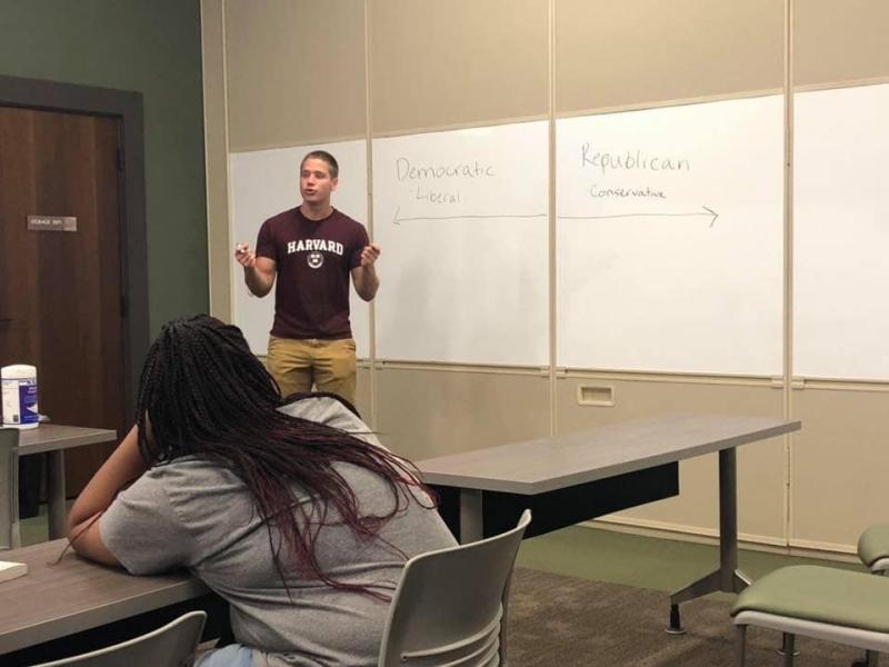 Student lecturing in front of a white board