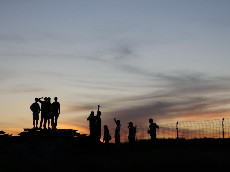 Silhouette of a group of people against a sunset background