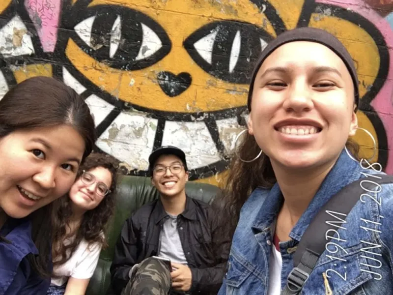 4 students in front of wall art in Paris.