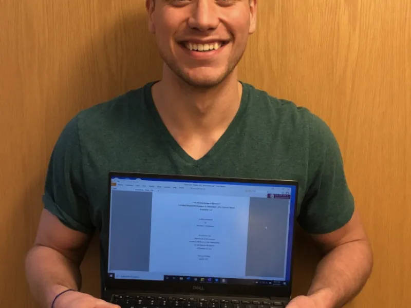 Student Holding a laptop in front of him