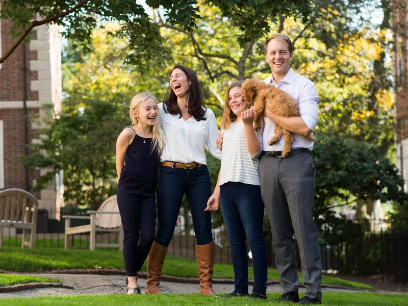 A portrait of Janine Santimauro and David Deming, faculty deans of Kirkland House, with their two daughters and dog.