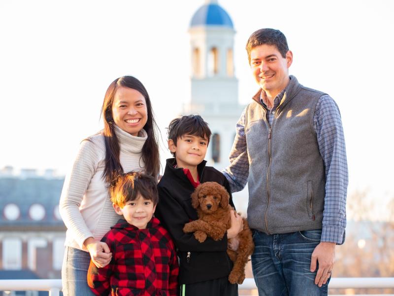 A portrait of Leslie Duhaylongsod and Eric Beerbohm, faculty deans of Quincy House, with their two sons and dog.