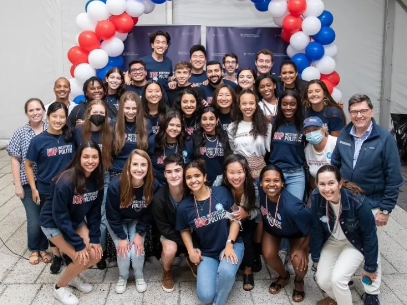 group of students in matching IOP t-shirts in front of red, white, and blue balloons