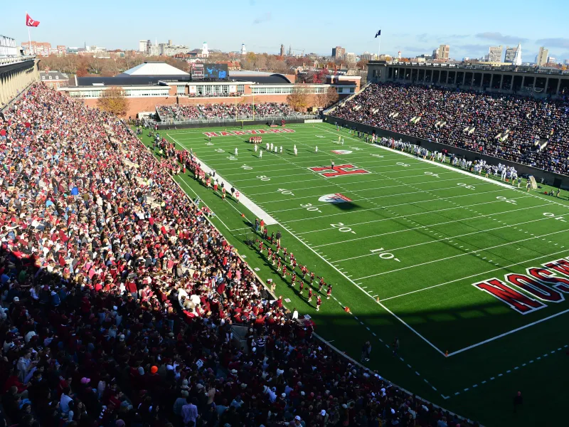 An upward view of Harvard Stadium filled with fans and football action on the field.