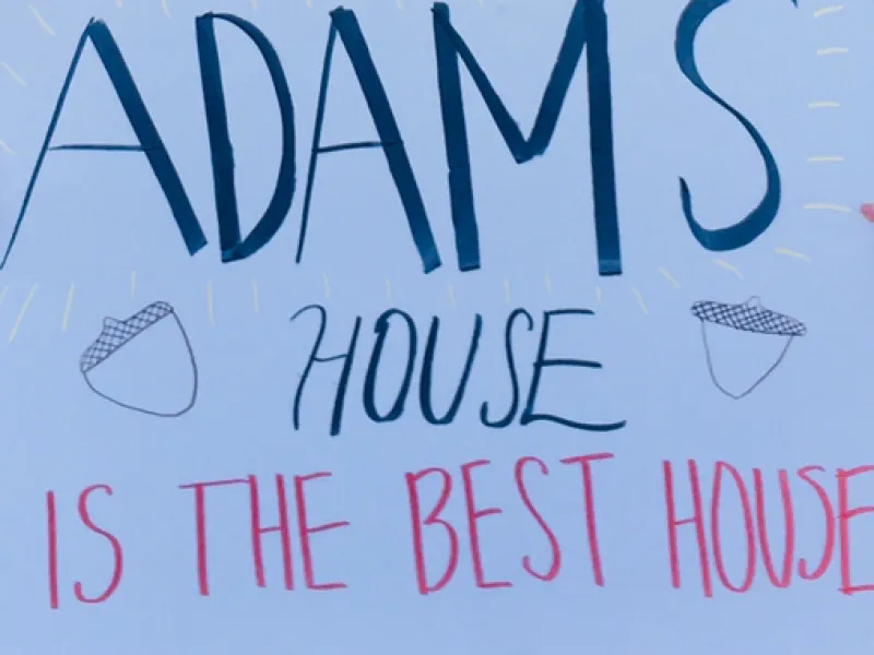 A picture of a white poster with "Adams House is the Best House" written on it.