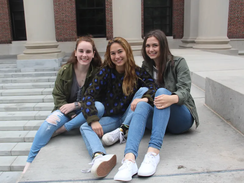 Three friends sitting in front of Widener Library