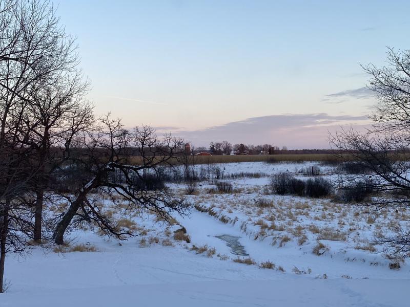 Image of a snowy field with a frozen stream at dawn. 