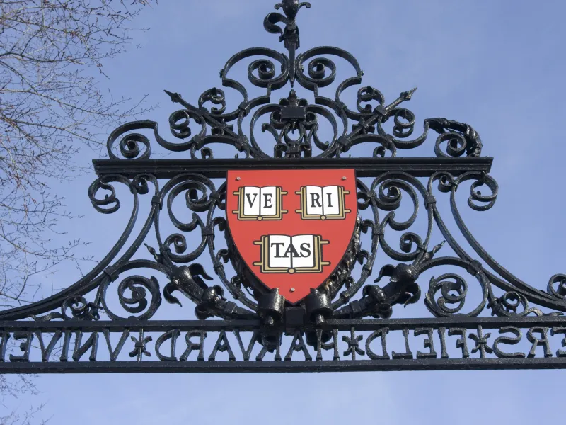 A harvard logo pinned to the top of a gate wall