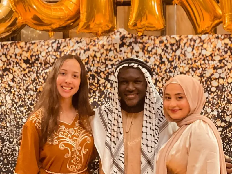 A group of friends and I wearing traditional clothing and posing in front of large balloons that spell out Sufra!