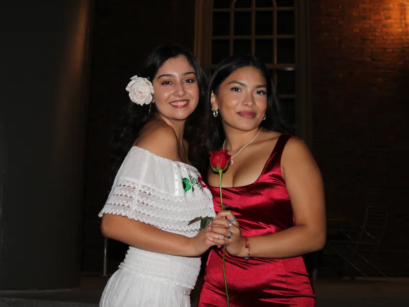 Latinx convocation a celebration for first years. Two girls holding a red rose.