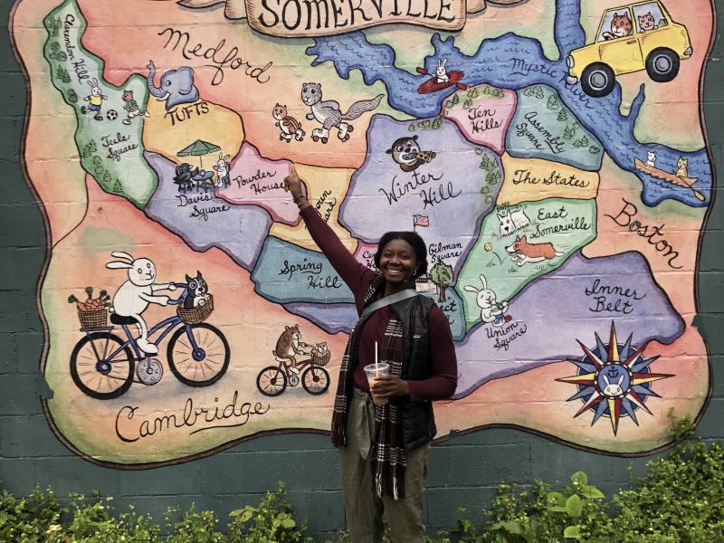 Martha Kebeh stands in front of a colorful map. 