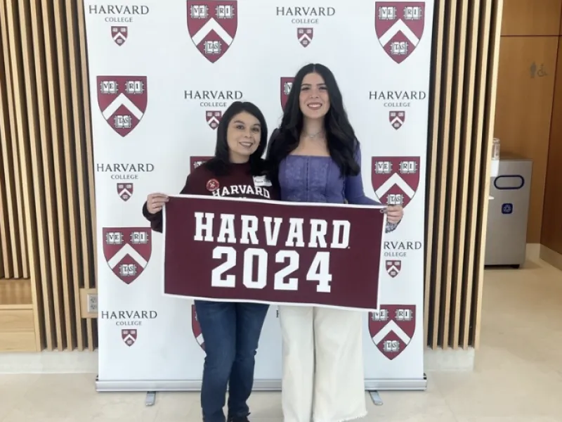 Mom and Daughter smiling with Harvard 2024 sign