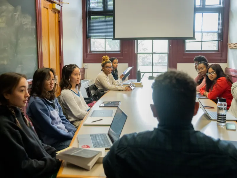 students and professors sitting around a table having a discussion
