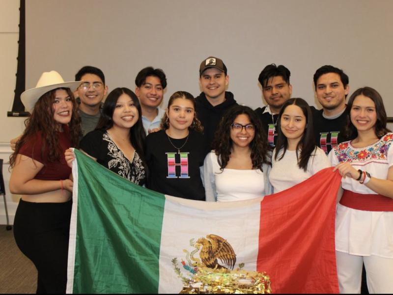 An image of the 11 board members for RAZA of the 2023 year.  They are holding up a Mexican flag. 