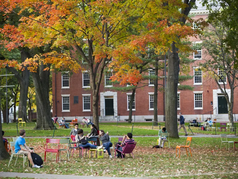 Image of students sitting on grass in front of building 
