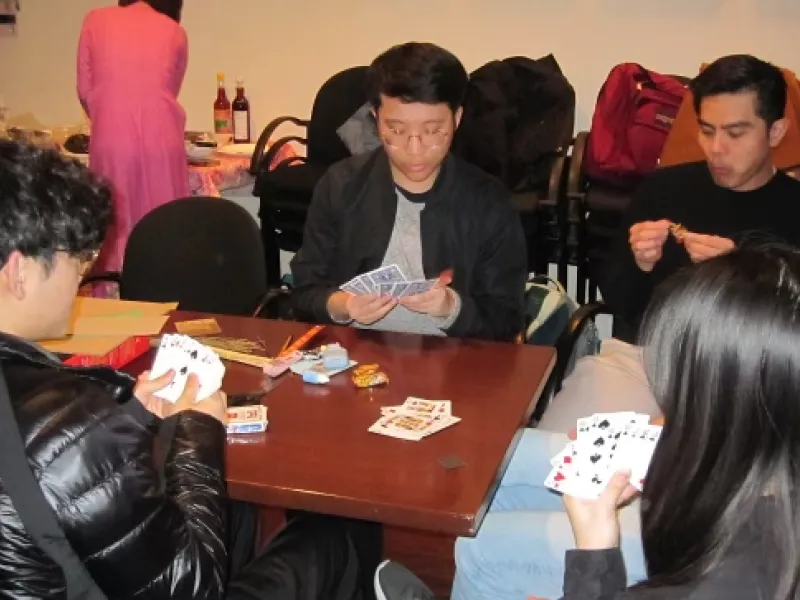 A group of five people playing cards at a table.