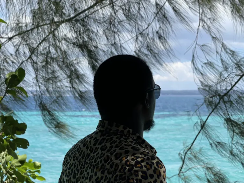 A photo of a man in sunglasses looking at blue ocean waters.