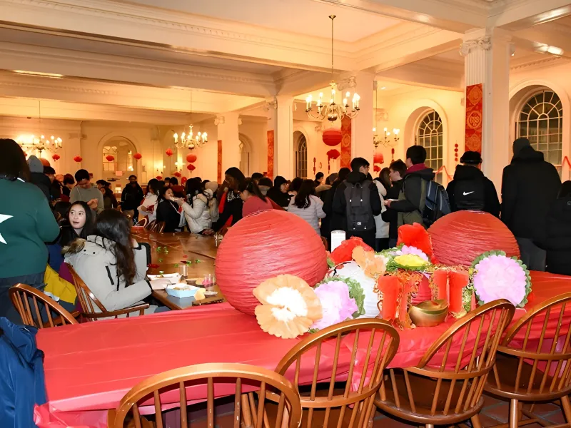 A crowded room decorated with red lanterns and festive decor, filled with people socializing around tables.