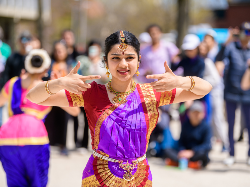 Dancer in traditional attire performing outdoors in front of a crowd.