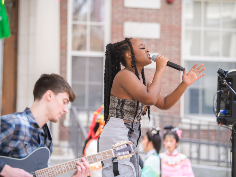 Singer performing with a guitarist at an outdoor event.