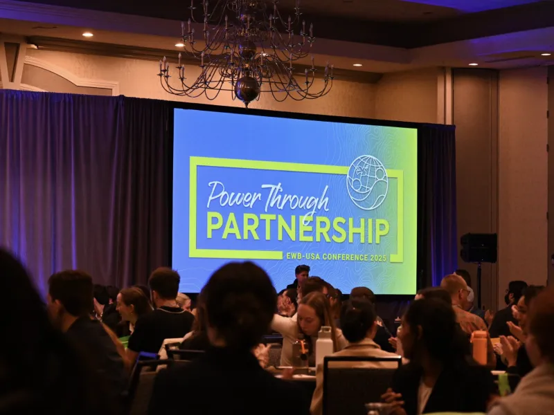 Slide with a blue background and green letters spelling "Power Through Partnerships."