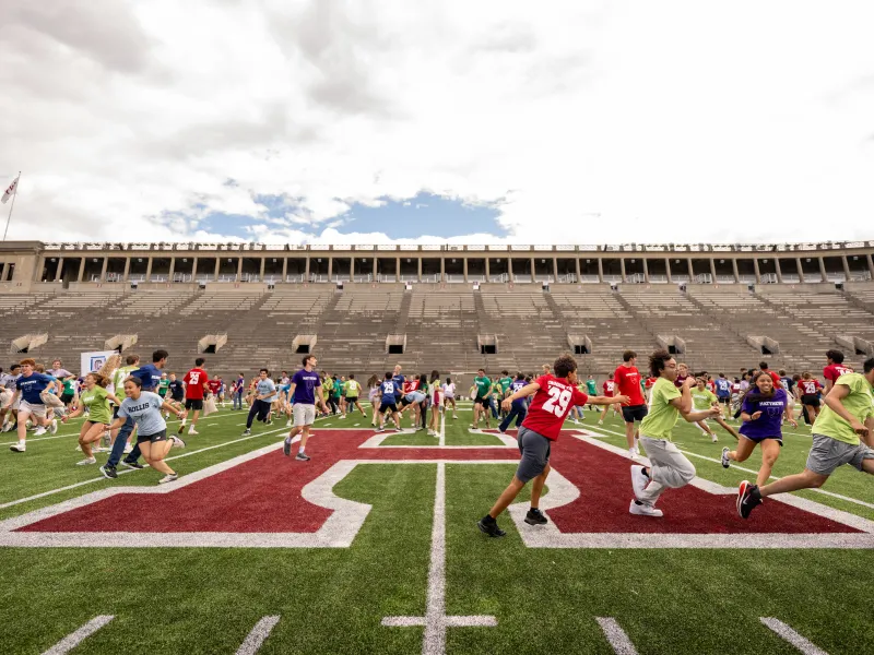 Members of the Class of 2029 run around the Harvard Athletics football field during a Crimson Kickoff class game. Photo by @fotobuddy.