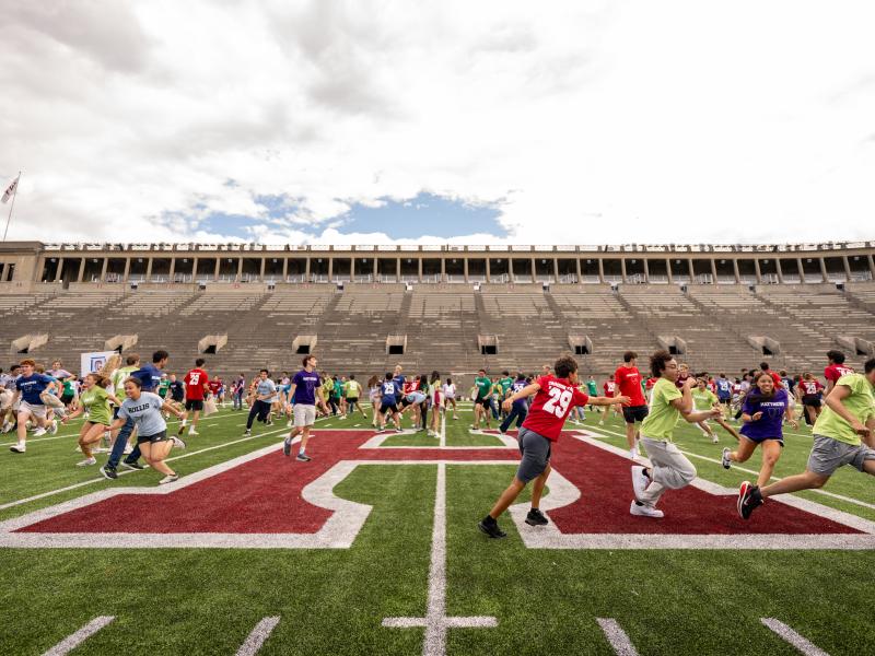 Members of the Class of 2029 run around the Harvard Athletics football field during a Crimson Kickoff class game. Photo by @fotobuddy.