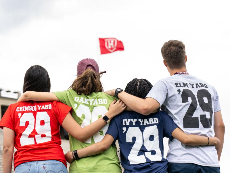 Class of 2029 students pose with their backs facing the camera, showing their various class shirts.
