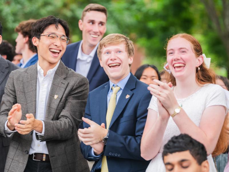 Three first-year students of the Class of 2029 smile widely next to each other and clap during the Convocation ceremony.