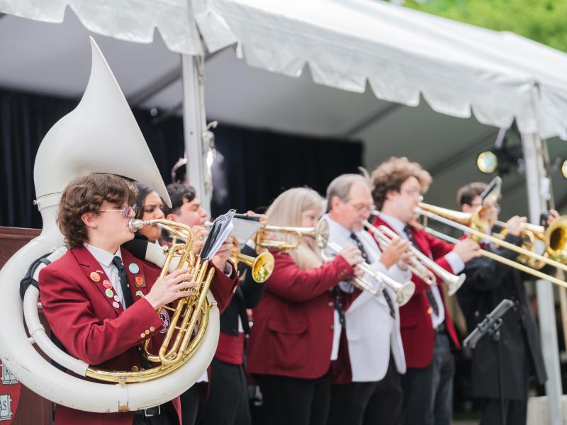 The Harvard University Band performing onstage during Convocation dressed in white and red suit jackets.