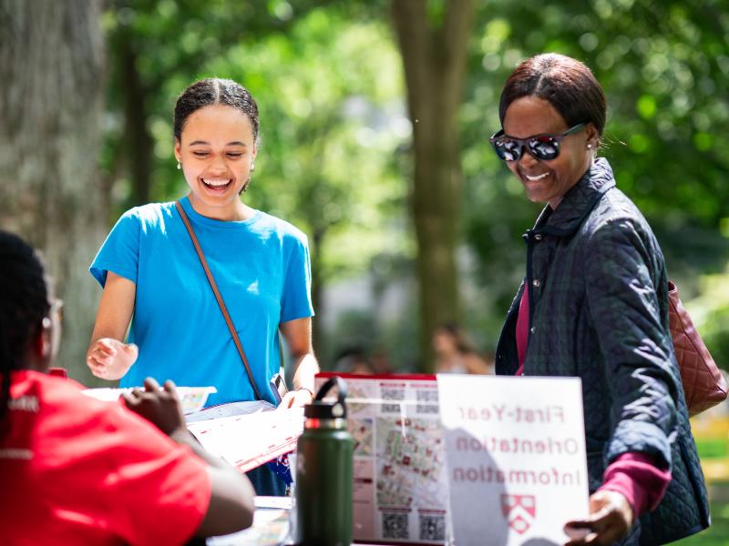 A first-year female student smiles alongside her mother while at the check-in table.