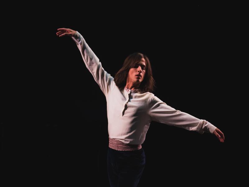 Person performing a dance on stage with arms outstretched.