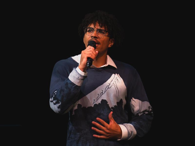 Person singing into a microphone on stage.