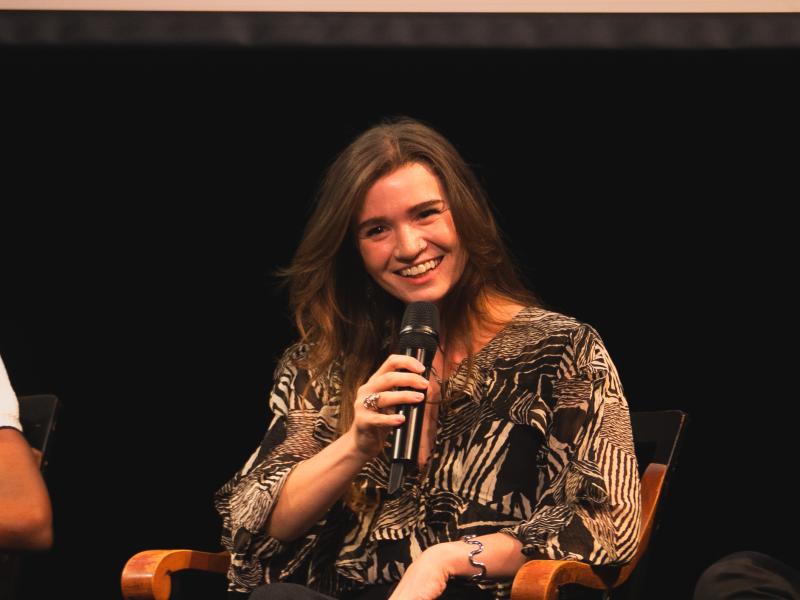 Woman sitting and smiling while holding a microphone.
