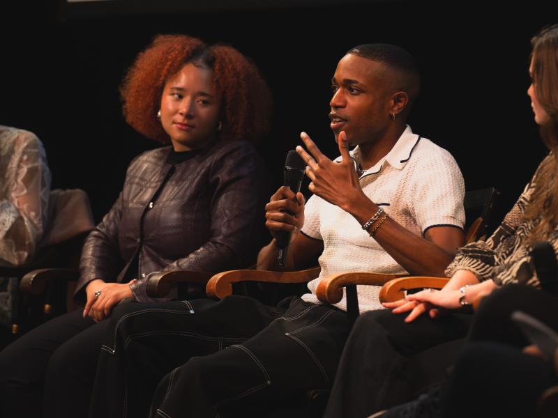Two people sit and speak into microphones during a panel discussion.