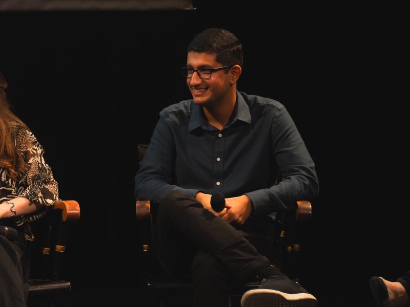 Person sitting and smiling while holding a microphone.
