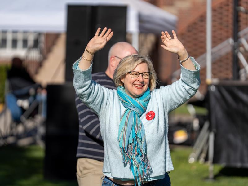 An older woman raises her hands in the air to celebrate winning a game.