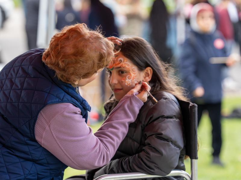A young girl is getting her face painted.