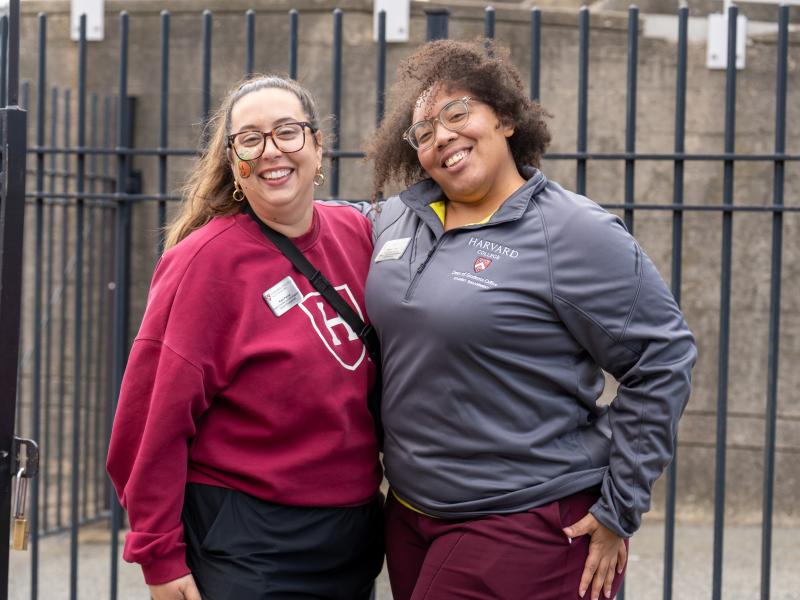 Two women in Harvard sweatshirts smile while posing for a photo together.