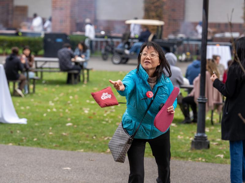 A woman throws a bean bag during a game of cornhole.